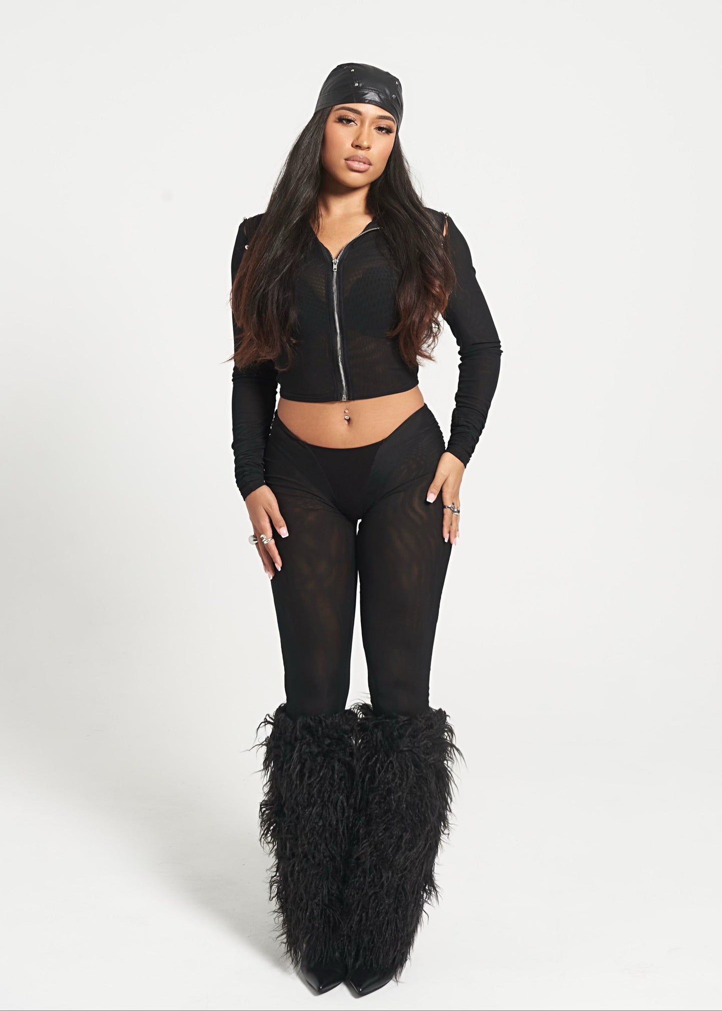 Person wearing a black outfit with a scarf and fluffy boots on a white background